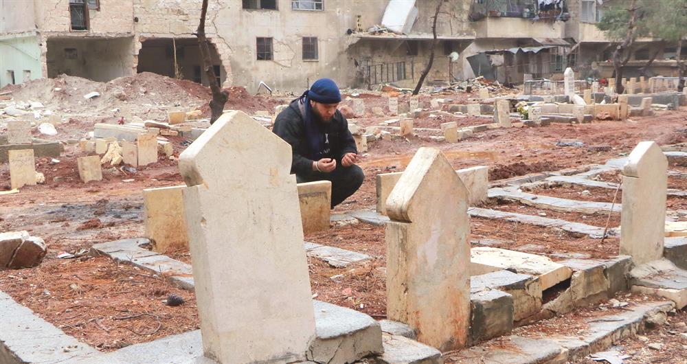 Halep'in doğusunda bina  aralarında oluşan  mezarlıklar katliamla  birlikte günden güne  büyüdü. Yakınları için dua  eden Halepliler, daha sonra  kuşatma altındaki  bölgeden çıkmanın  yollarını arıyor. 