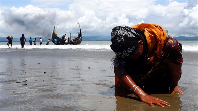 An exhausted Rohingya refugee woman touches the shore after crossing the Bangladesh Myanmar border by boat through the Bay of Bengal in Shah Porir Dwip Bangladesh