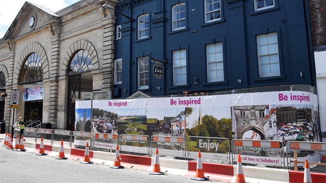 People stand outside the Zizzi restaurant which remains behind barriers after it was closed following the nerve agent attack on Sergei Skripal and his daughter Yulia, in Salisbury, Britain, June 22, 2018. 