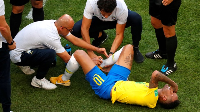 Brazil's Neymar receives treatment from medical staff after sustaining an injury