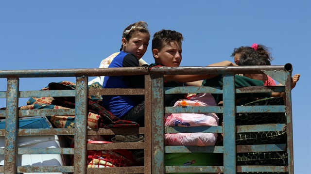 Children ride on a truck with belongings in Deraa countryside, Syria