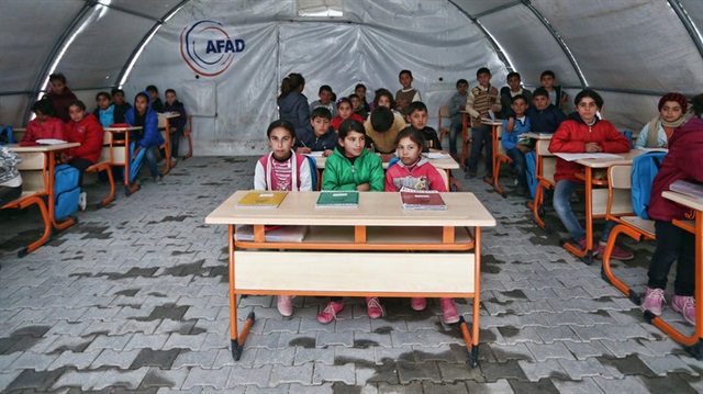 Syrian children listen to a teacher during a lesson in a temporary classroom in the Suruc refugee camp.