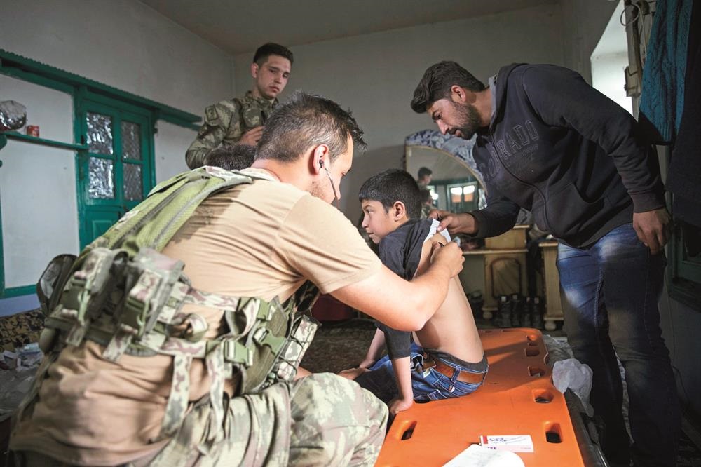 جنود أتراك وسوريون من المعارضة يشرفون على علاج طفل بعفرين.