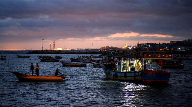 Palestinian fishermen ride their boats 