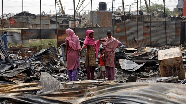 Rohingya women stand on the debris of their houses after a fire broke out in their camp