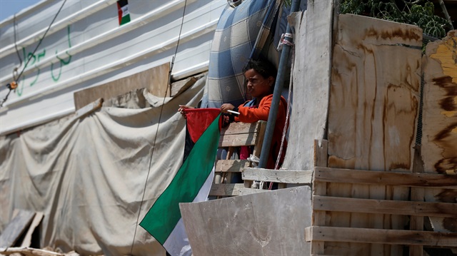 A girl holds a Palestinian flag as she looks out from a dwelling in the Bedouin village of Khan al-Ahmar