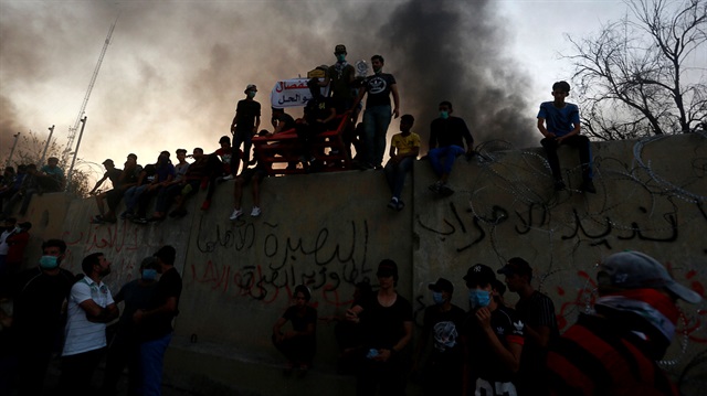 Iraqi protesters stand on concrete blast walls during an anti-government protest near the burnt building of the government office in Basra, Iraq September 7, 2018. 