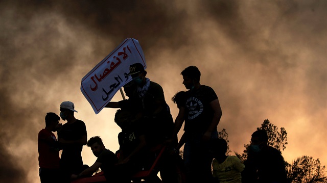Protesters stand on concrete blast walls during anti government protest near the building of the government office in Basra, Iraq 