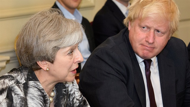 Theresa May sits next to Boris Johnson