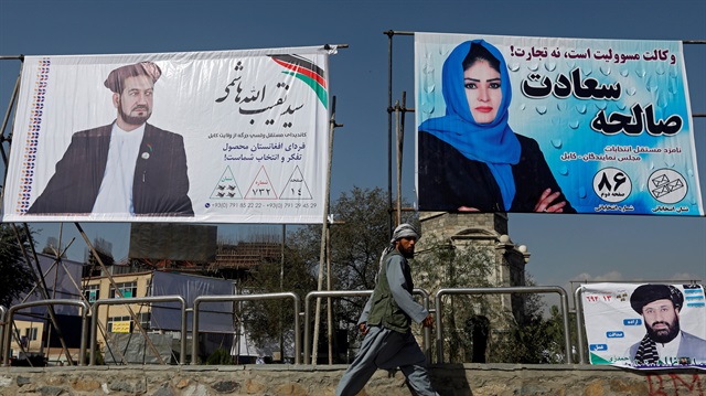 An Afghan man walks in front of election posters of parliamentarian candidates installed on the first day of elections campaign in Kabul, Afghanistan September 28, 2018. 