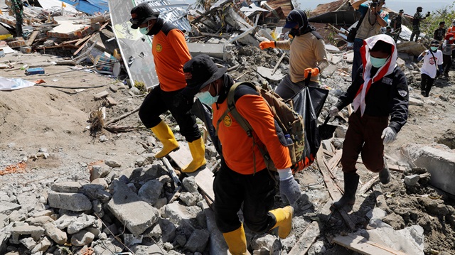 Rescue team members carry a dead body after an earthquake hit Petobo neighbourhood in Palu, Indonesia, October 5, 2018. 
