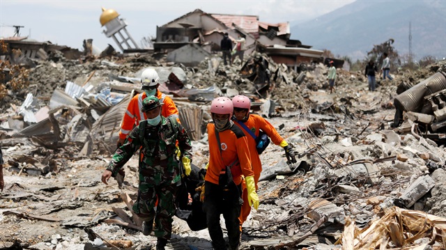 Rescue workers and a soldier remove a victim of last week's earthquake in the Balaroa neighbourhood in Palu, Central Sulawesi, Indonesia October 6, 2018