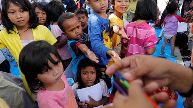 Children reach for coloured pencils while attending a class at a camp for displaced people following the earthquake and tsunami in Palu, Central Sulawesi, Indonesia October 8, 2018