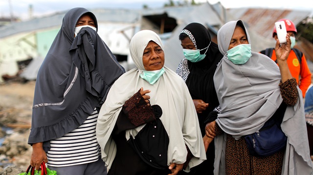 Women react as they see an excavator pulling a body from the rubble at Balaroa neighborhood hit by the earthquake and liquefaction in Palu, Central Sulawesi, Indonesia, October 9, 2018. 