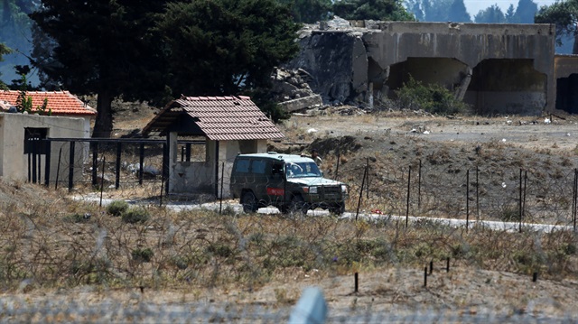 A man stands next to an ambulance at the Quneitra border crossing between Israel and Syria, as seen from the Israeli-occupied Golan Heights July 21, 2018. 