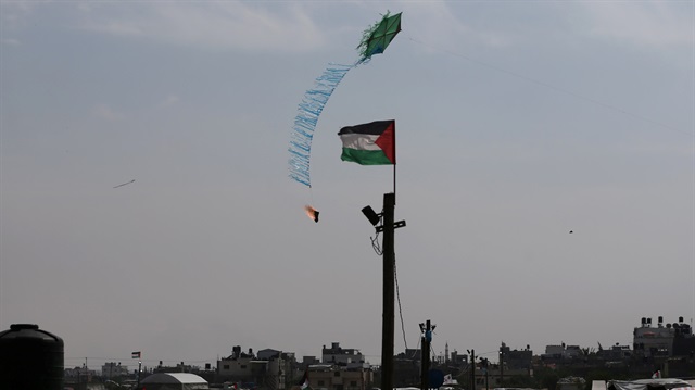 A kite is set on fire by Palestinians to be thrown at the Israeli side during clashes at a protest demanding the right to return to their homeland, at the Israel-Gaza border in the southern Gaza Strip, April 27, 2018. 