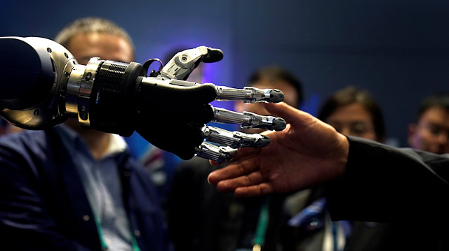 A man tries to shake hands with SCHUNK 5-finger anthropomorphic gripper hand during the China International Import Expo (CIIE), at the National Exhibition and Convention Center in Shanghai, China November 6, 2018. 