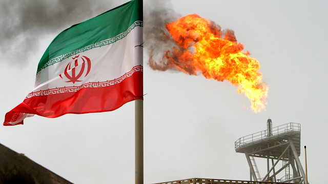 A gas flare on an oil production platform in the Soroush oilfields is seen alongside an Iranian flag in Iran, July 25, 2005. 