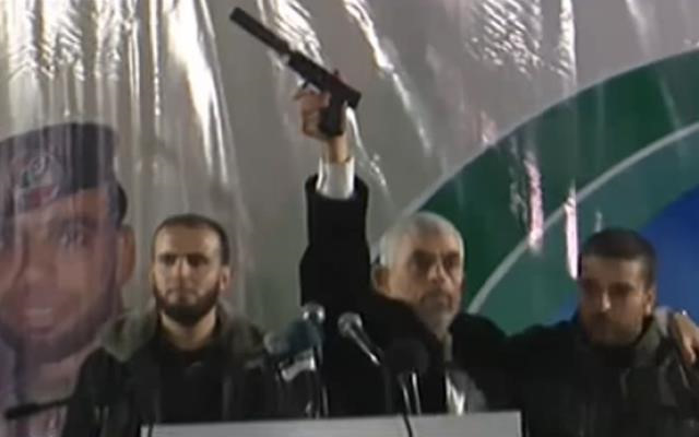 Yahya Sinwar holds up a gun with a silencer.
