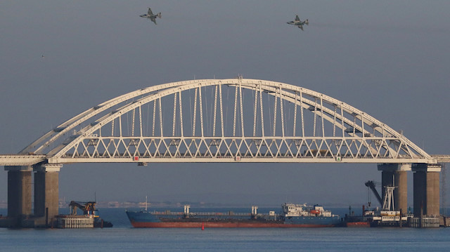 Russian jet fighters fly over a bridge connecting the Russian mainland with the Crimean Peninsula with a cargo ship beneath it after three Ukrainian navy vessels were stopped by Russia from entering the Sea of Azov via the Kerch Strait in the Black Sea, Crimea.