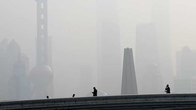 People walk on a bridge in front of the financial district of Pudong, which is covered in smog, during a polluted day in Shanghai, China November 28, 2018. 