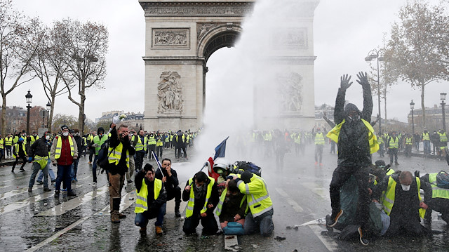 Protesters wearing yellow vests, a symbol of a French drivers' protest against higher diesel taxes, stand up in front of a police water canon at the Place de l'Etoile near the Arc de Triomphe in Paris, France, December 1, 2018. 