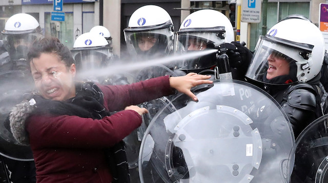 Brüksel'de bir göstericiye tazyikli su sıkan polis.