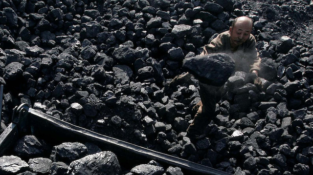 Çinli bir adam, 19 madencinin öldüğü Shaanxi bölgesindeki bir arabaya kömür yüklüyor. Fotoğraf: Reuters