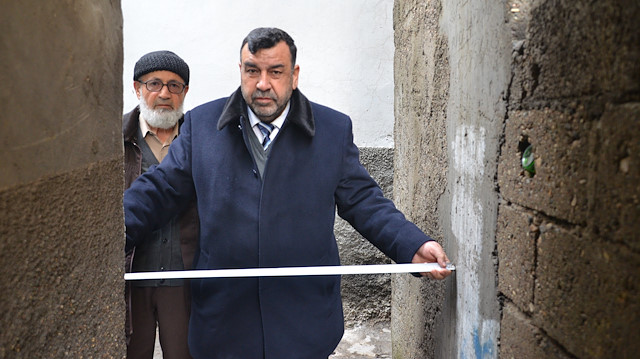 Genişliği 90 santim olan sokakta metreyle ölçüm yapan vatandaşlar.