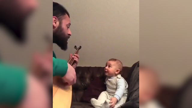 Babasından Bil oğlum türküsünü hayranlıkla dinleyen bebek