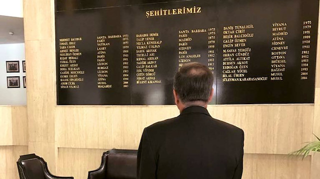 Büyükelçi, bugüne kadar şehit edilen Türk diplomatlar için oluşturulan anıt duvarın önünde poz verirken. Tarih 10 Temmuz 2019.