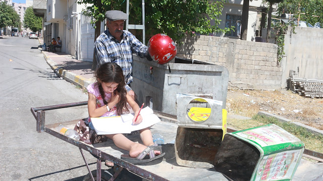 Babasının çöpten topladığı kitapları okuyor